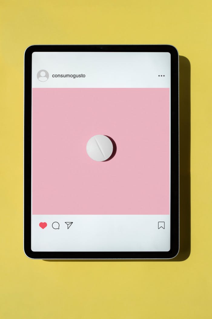 A tablet showing a minimalist pink design on a vibrant yellow surface, featuring an Instagram-like layout.